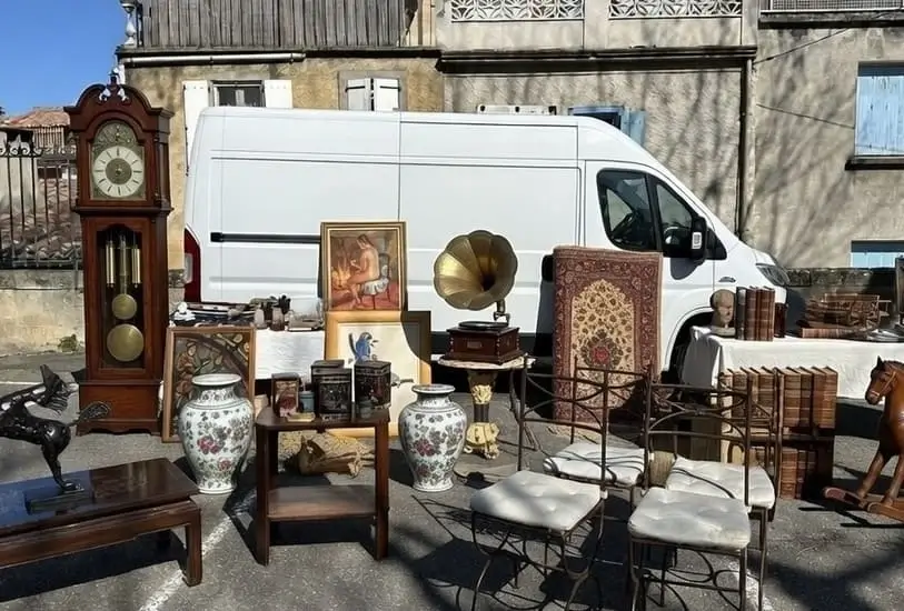 Belle sélection d’objets chinés en brocante avec horloge comtoise, gramophone à cornet doré, vases en porcelaine et chaises vintage, exposés devant le camion utilitaire Seb Troc